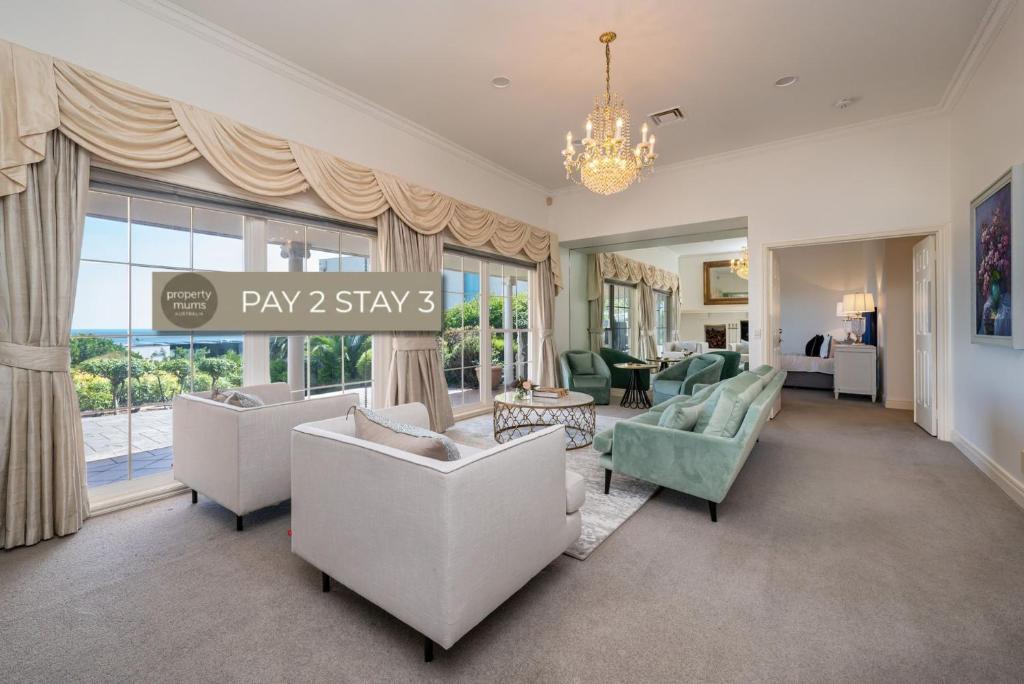 a living room with white furniture and a large window at Pelican Views in Mount Eliza