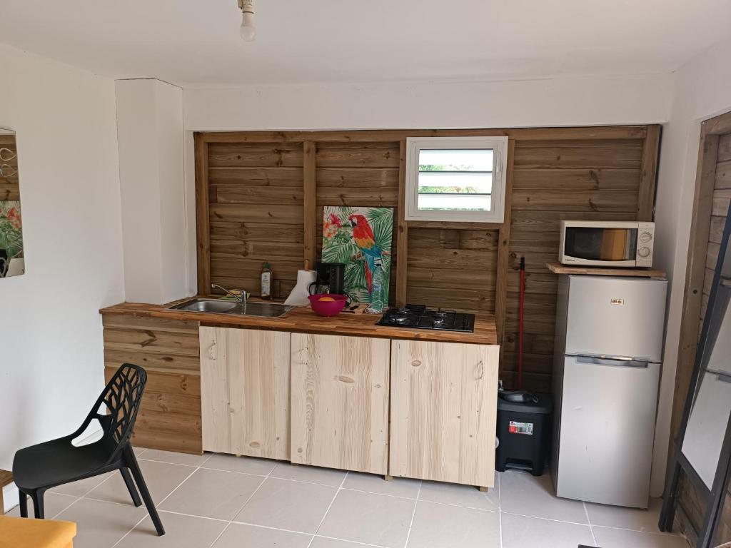 a kitchen with wooden cabinets and a microwave at Escale moulienne in Le Moule