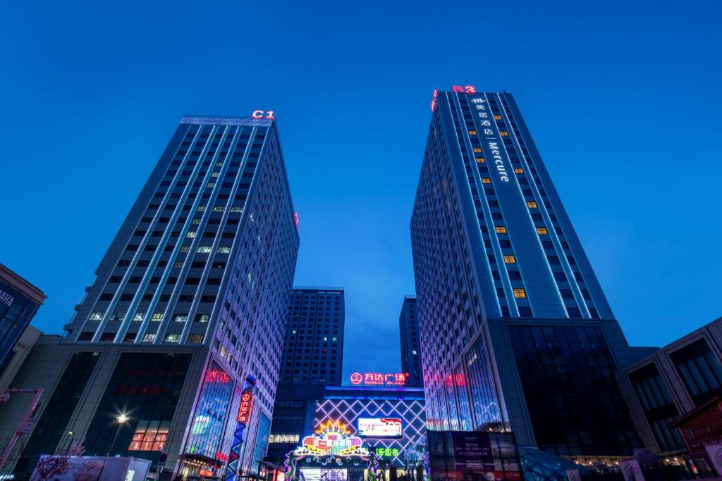 two tall skyscrapers in a city at night at Mercure Urumqi Doowin Wanda Plaza in Ürümqi