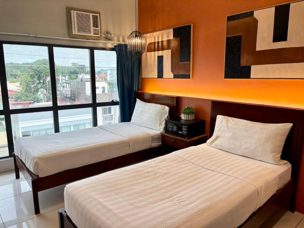 ein Hotelzimmer mit zwei Betten und einem Fenster in der Unterkunft Pacific Park Hotel in Manila