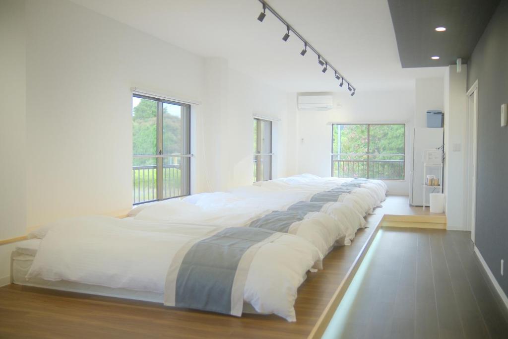 a large white bed in a room with windows at Private Stay EN SUMOTO in Sumoto