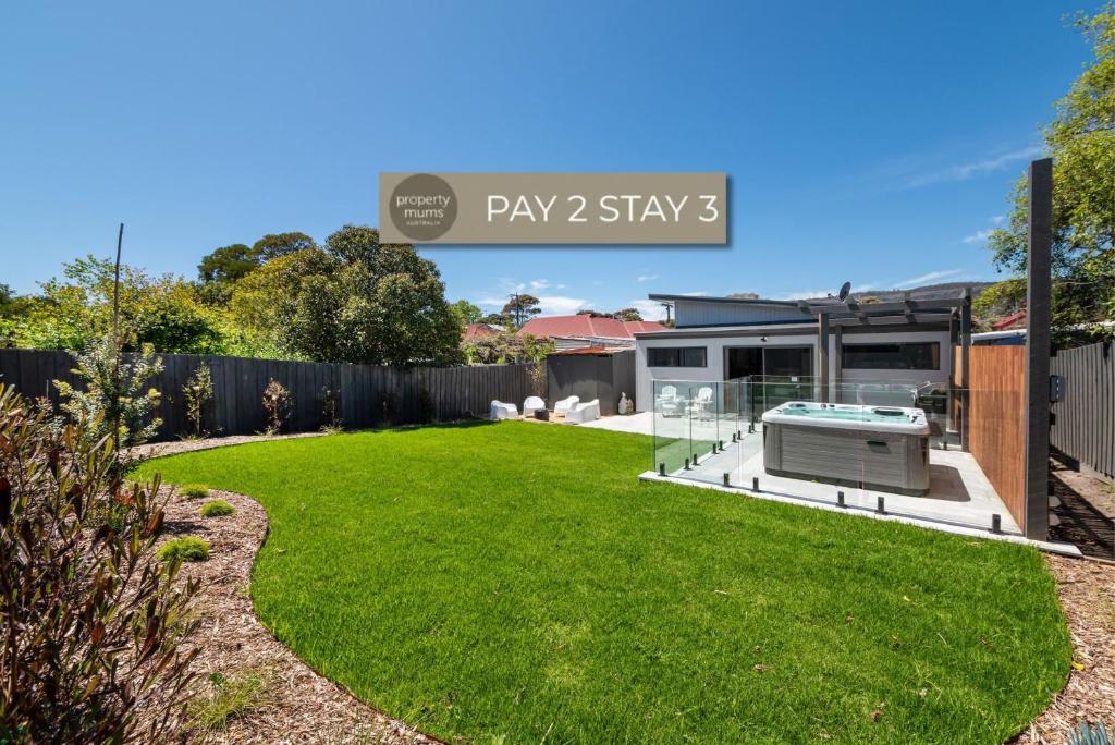 a backyard with a lawn and a play yard sign at Kennington Beach Getaway with Spa in Rosebud