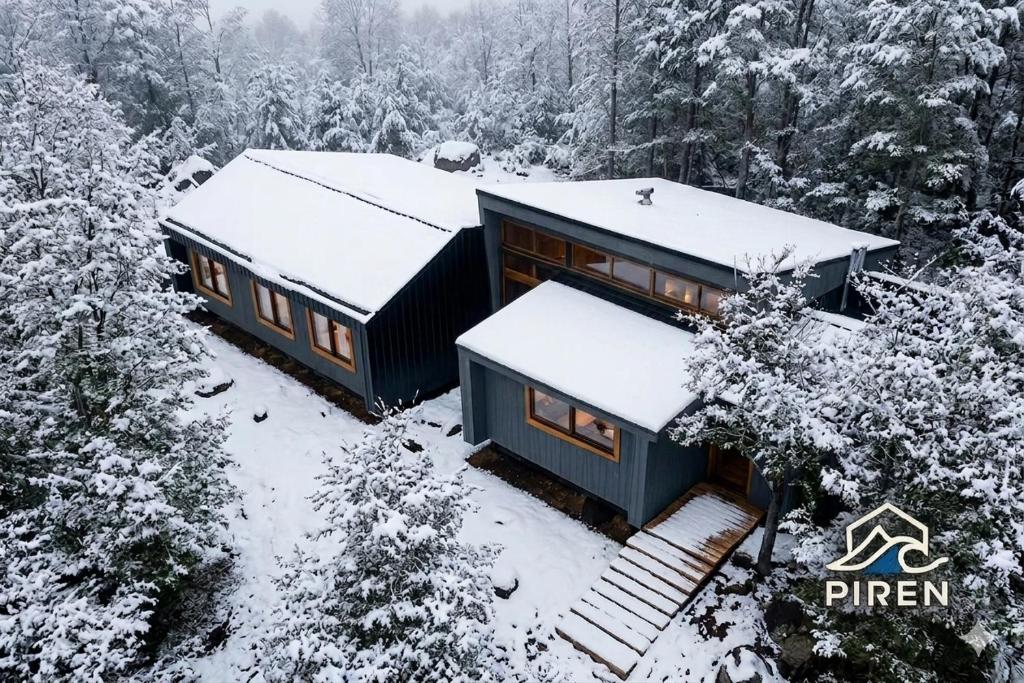 a house covered in snow in the woods at Refugio PIREN, Corralco, Hot Tub y nieve in Curacautín