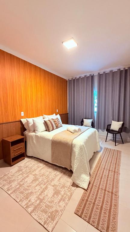 a bedroom with a large bed and a rug at Suíte Ipê-Amarelo in Camanducaia