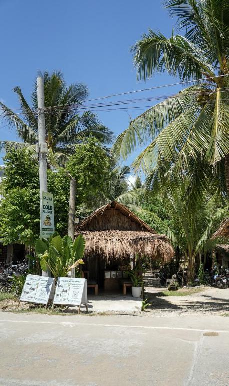 a building with a straw hut with palm trees at Kabilin Homestay in General Luna
