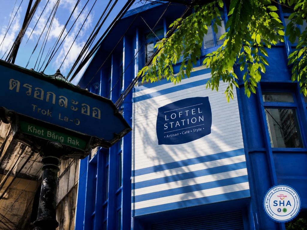 a blue and white building with a sign on it at Loftel Station Hostel in Bangkok