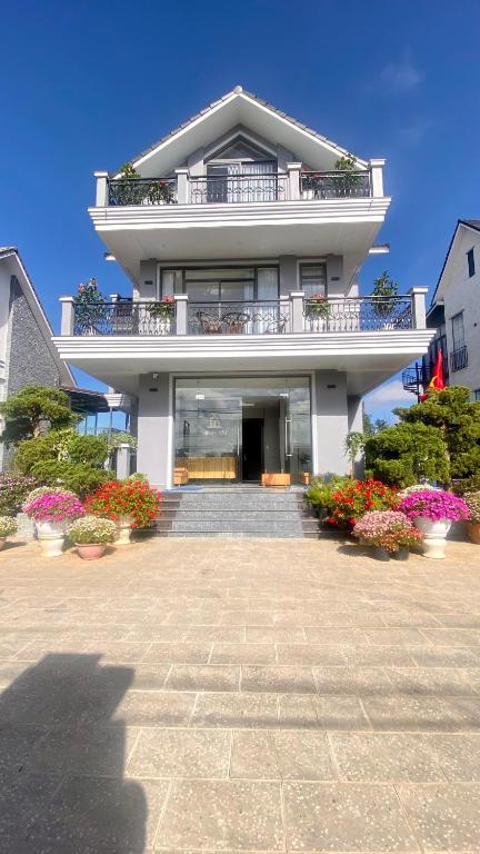 a large white building with a balcony and flowers at Minh An Villa in Da Thanh