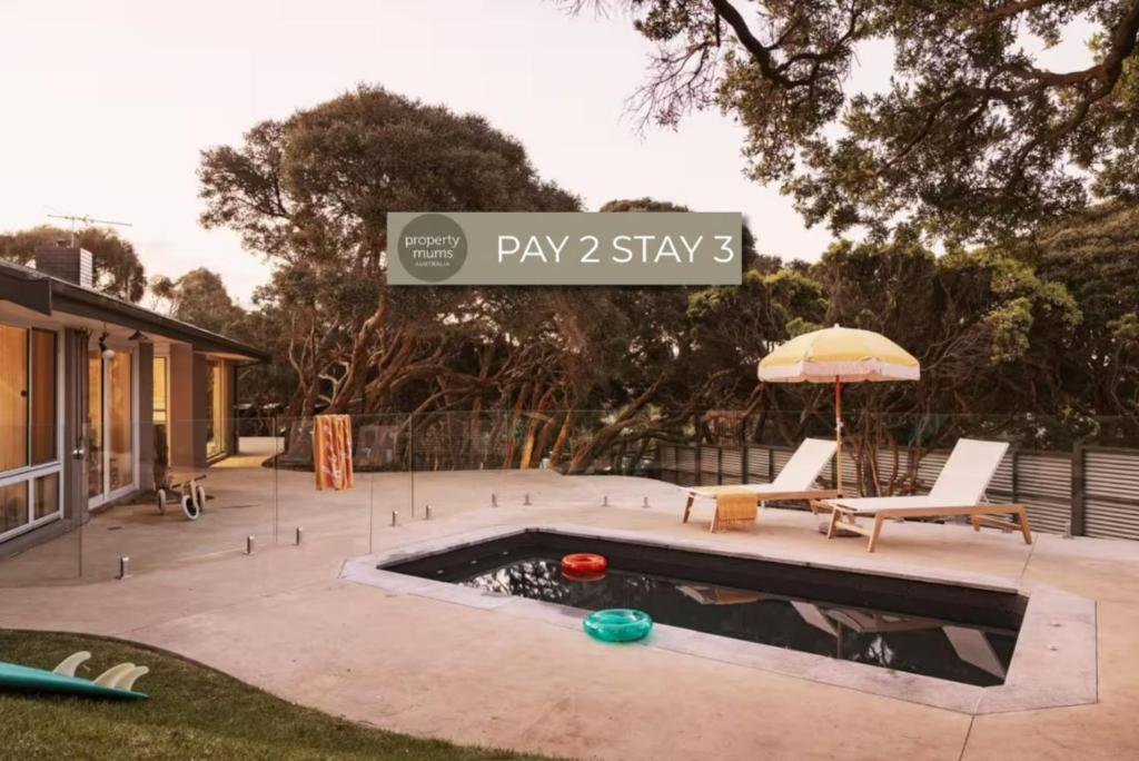 a patio with a pool and an umbrella and chairs at Hilarys Hideout with heated pool in Rye