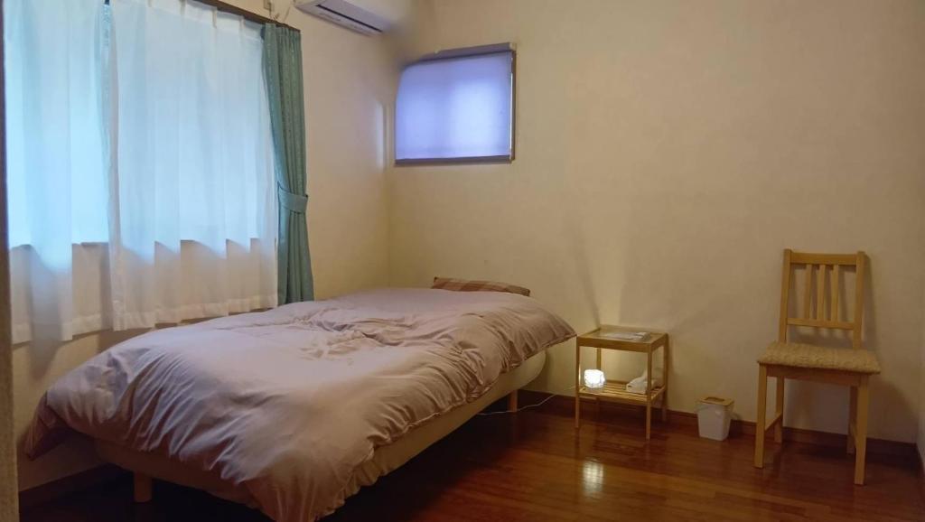 a bedroom with a bed and a window and a chair at 民泊kururu 個室 鍵付き朝パン付きライダー用ガレージ有り in Nishidani