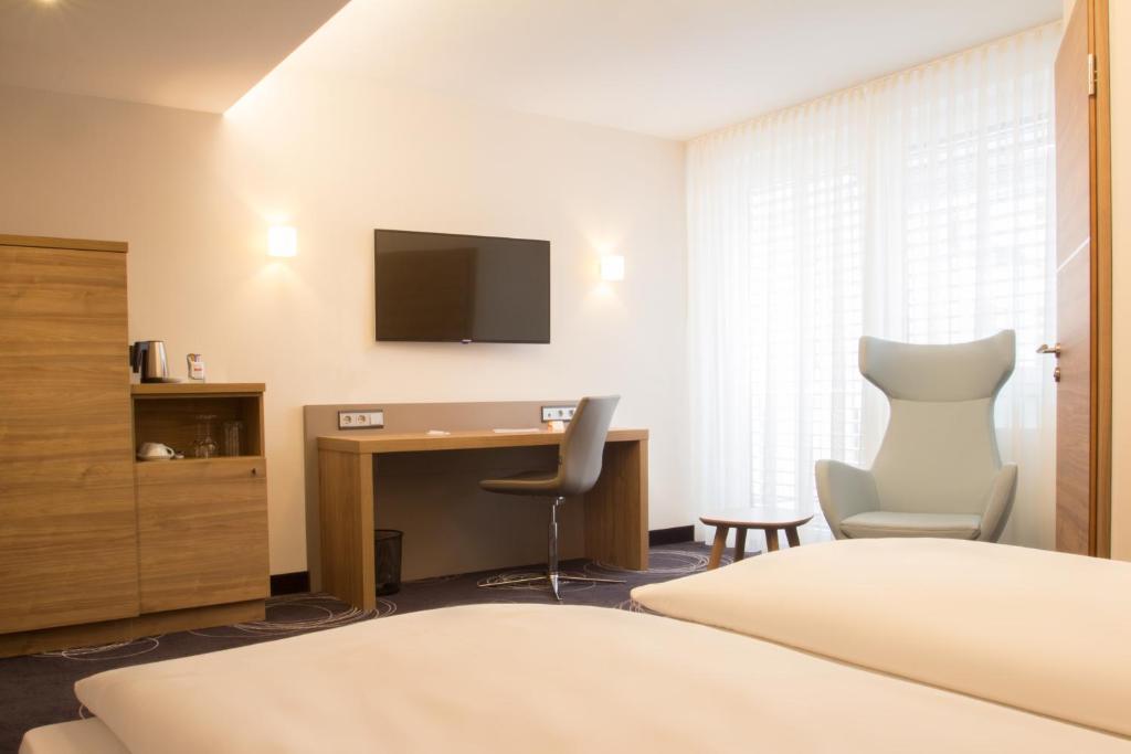 Habitación de hotel con escritorio y TV en Hotel Rio en Karlsruhe