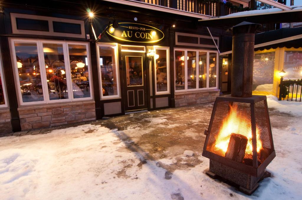 a building with a fire outside of it in the snow at Hotel Mont-Tremblant in Mont-Tremblant