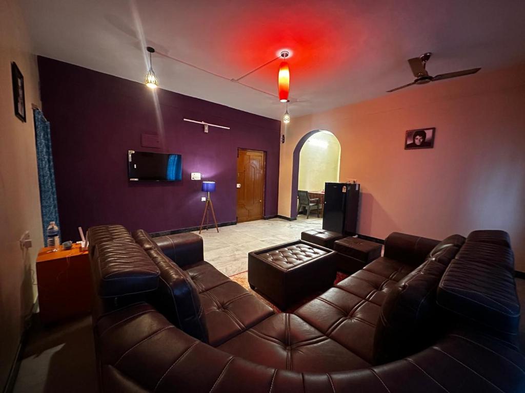 a living room with a leather couch and a tv at IP Home stays in Pondicherry