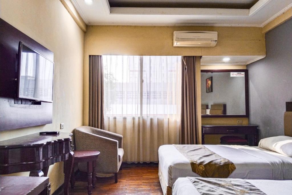 a hotel room with two beds and a desk at SNUZ Hotel Menteng in Jakarta