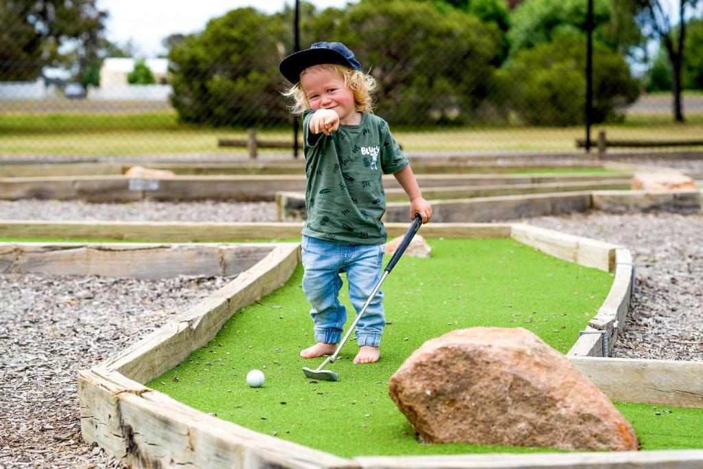 a young child playing golf in a park at Horsham Holiday Park in Horsham
