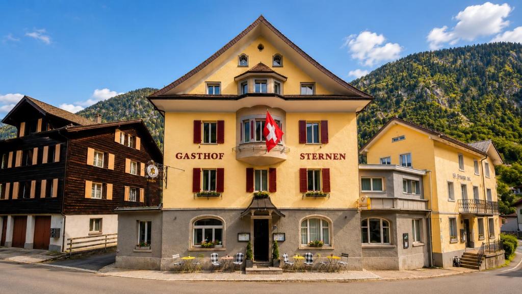a large yellow building with a flag on it at Hotel Sternen Gurtnellen AG in Gurtnellen