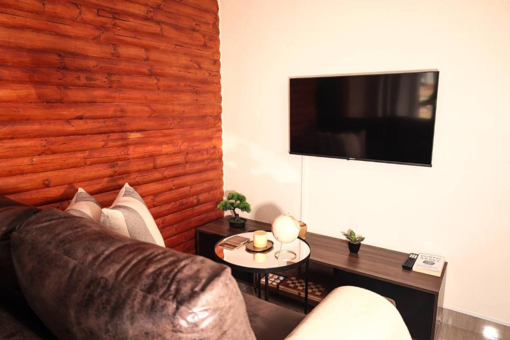 a living room with a leather couch and a table at Elite Garden Cabin, Cozy Hideaway in Welkom with Fast WiFi, Free Parking in Welkom