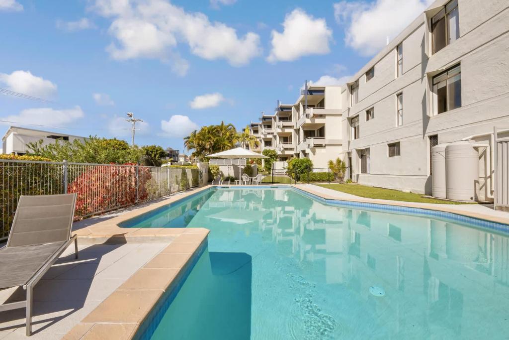 a swimming pool in front of a building at Warroo Apartments in Alexandra Headland