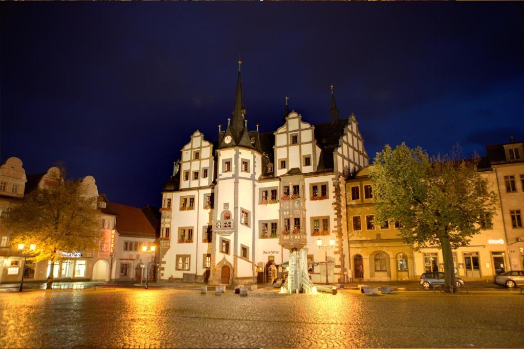 a large white building with a statue in front of it at Hotel Anker in Saalfeld