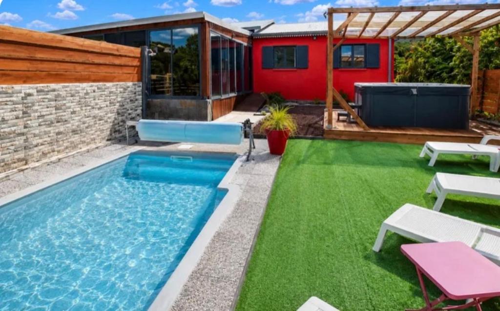 a small backyard with a swimming pool and green grass at Villa Le Cyprès classée 4 Etoiles billard, piscine et jacuzzi in Saint-Joseph