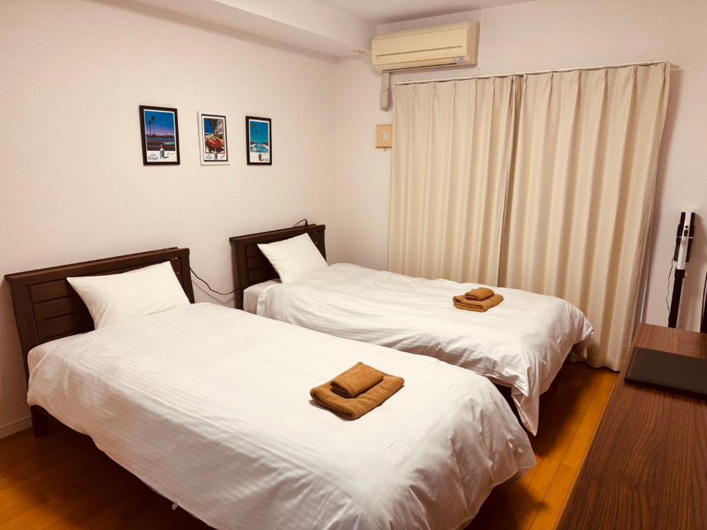 two beds in a hotel room with towels on them at オンブラージュ九品寺203-無料駐車場付き-繁華街まで徒歩圏内-南向きで明るいワンルーム in Kumamoto