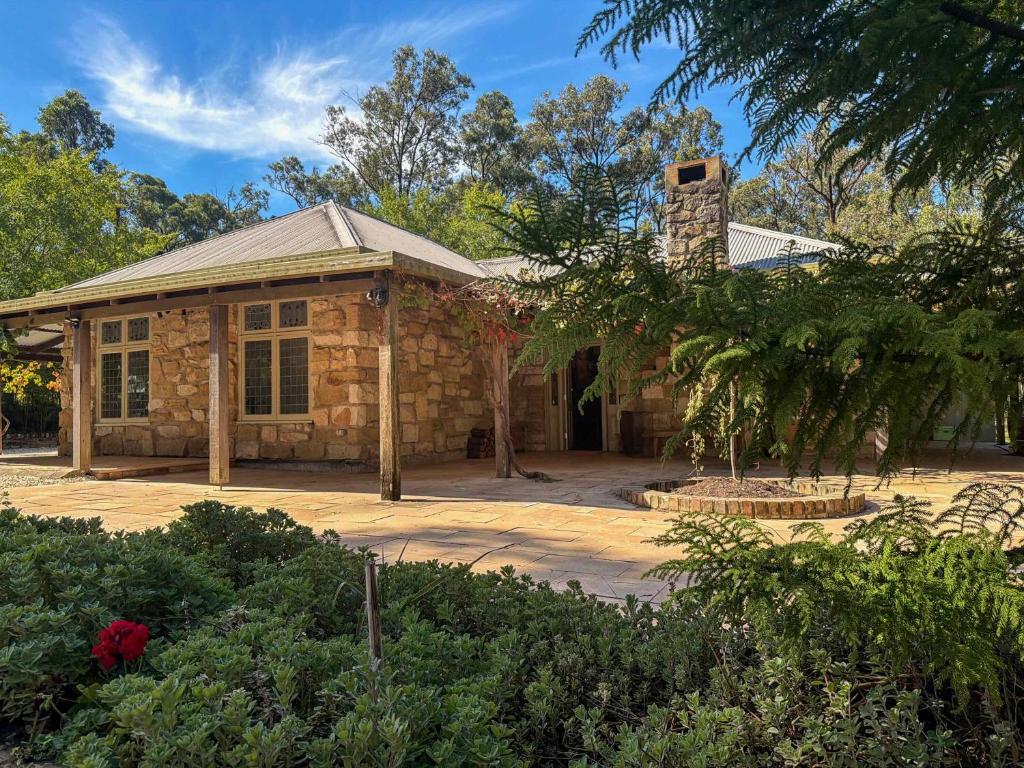 a stone house with a tree in front of it at Highwoods Cottage in Pokolbin