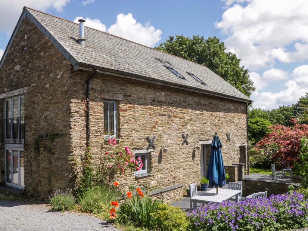 a stone house with flowers in front of it at The Hay Barn in Halwell