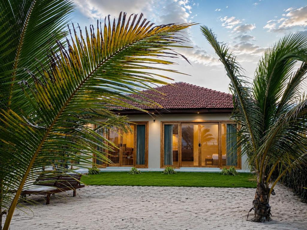 a house with a palm tree in front of it at Beach Escape in Arugam Bay
