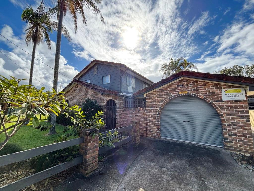 a brick house with a garage and palm trees at Arcos in Hat Head
