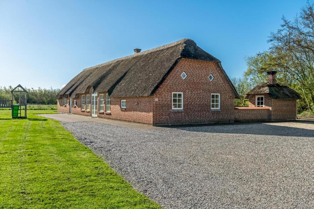 a large red brick building with a thatched roof at Feriehus 2033 in Ulfborg