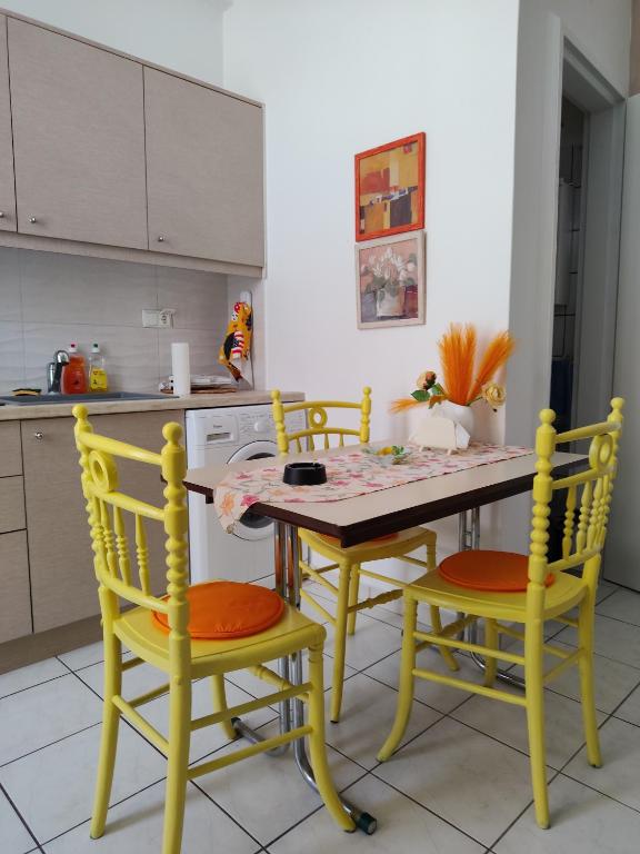 a kitchen with yellow chairs and a table and a table and a counter at Manolia !!! in Kranidi
