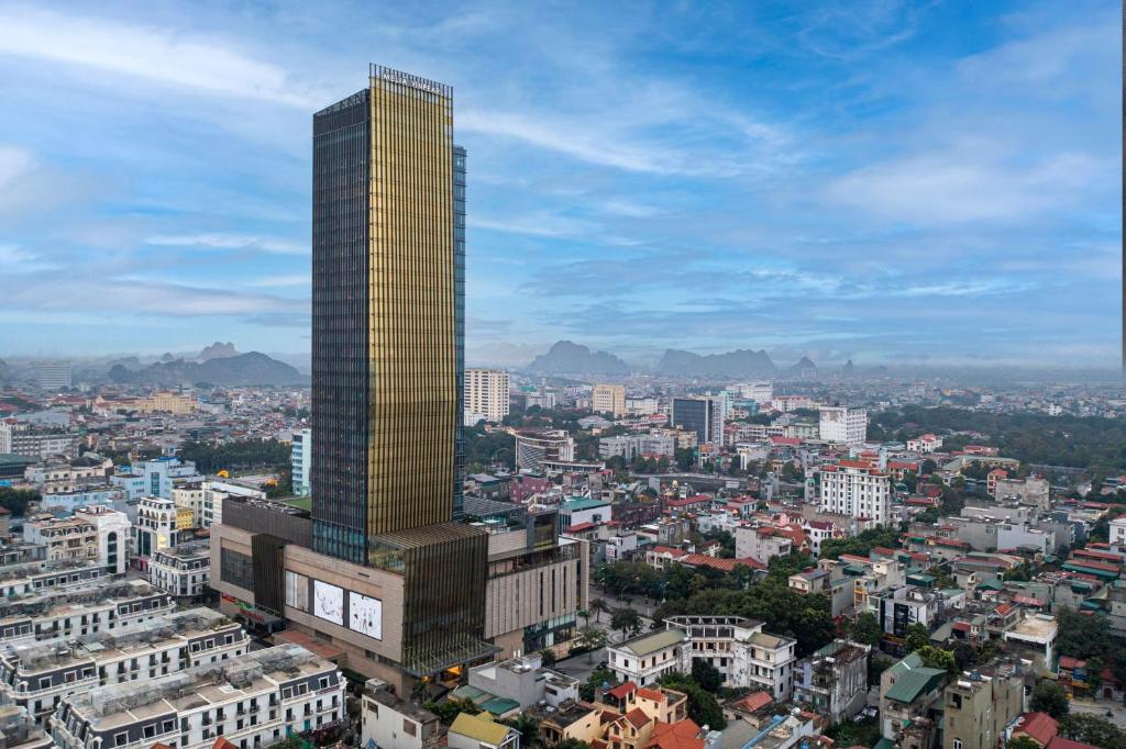a tall yellow skyscraper in the middle of a city at Meliá Vinpearl Thanh Hoa in Thanh Hóa