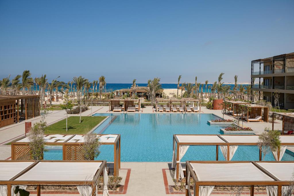 a resort with a pool and tables and the beach at Sakhra Hotel & Spa, Almaza Bay in Marsa Matruh