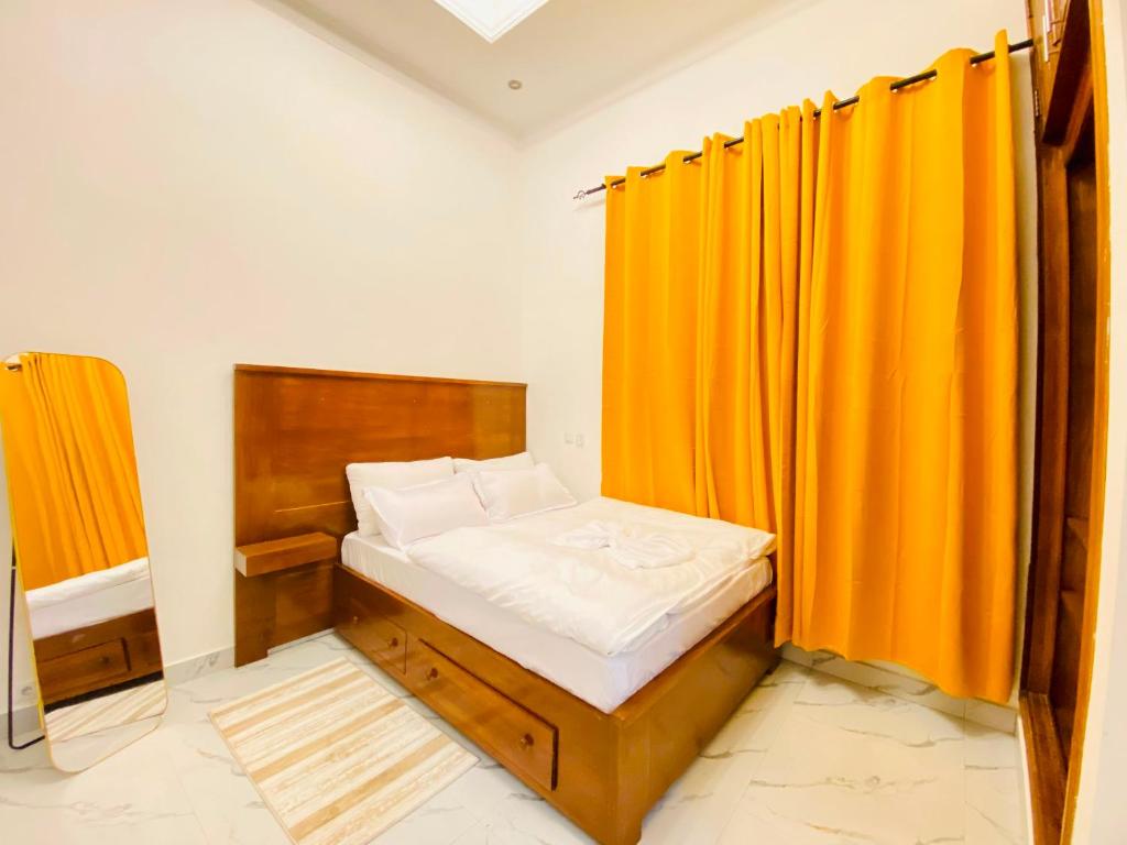 a small bedroom with an orange curtain and a bed at Résidence moncloa in Brazzaville