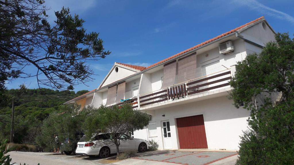 a white building with a car parked in front of it at Apartments Irena in Božava