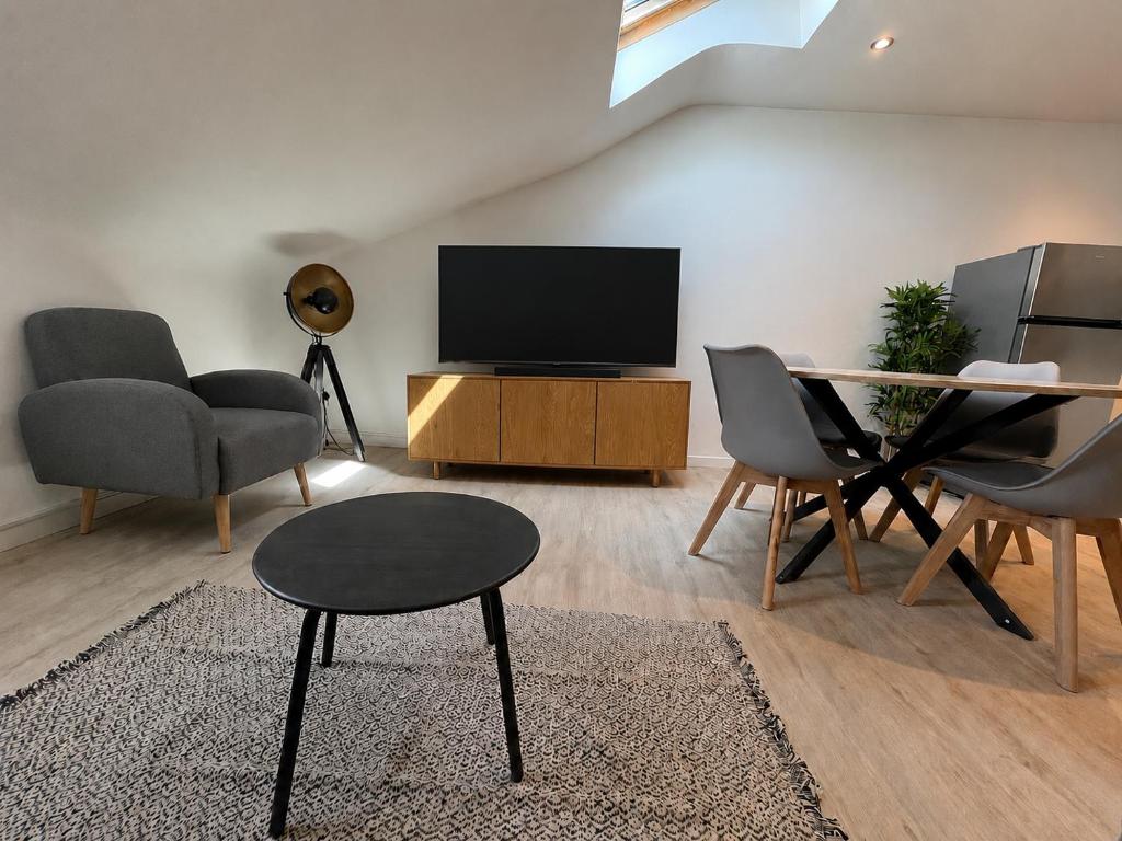 a living room with a tv and chairs and a table at vannes évasion in Vannes