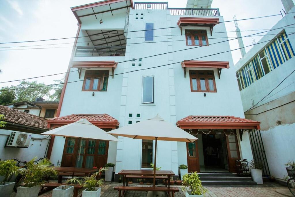 two tables with umbrellas in front of a building at Panda House in Galle