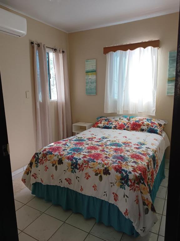 a bedroom with a bed with a floral bedspread at Private 1 Bedroom shared house in La Ceiba