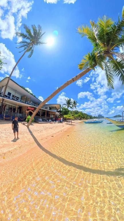 a man standing on a beach with a palm tree at Islandfront El Nido in El Nido
