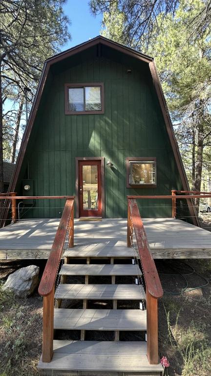 a green house with a bench in front of it at Cozy Alpine A-Frame in Flagstaff