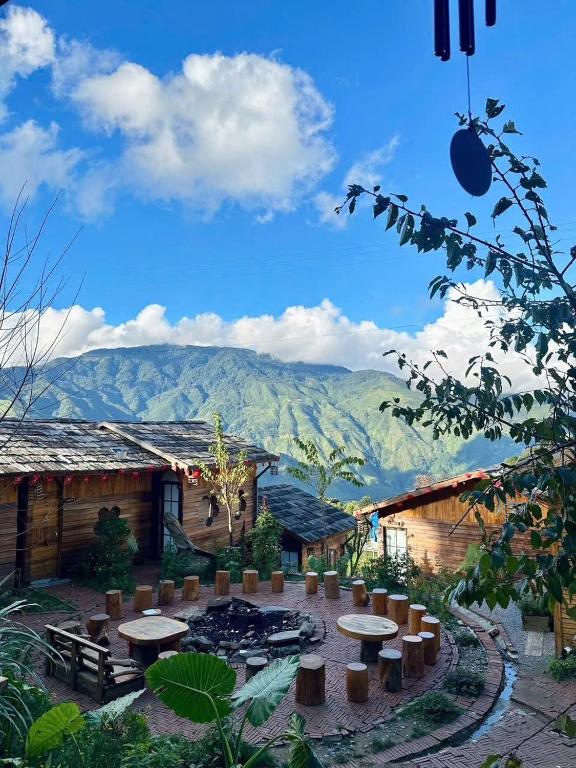 a patio with tables and chairs and mountains in the background at Mando Homestay in Bắc Yên