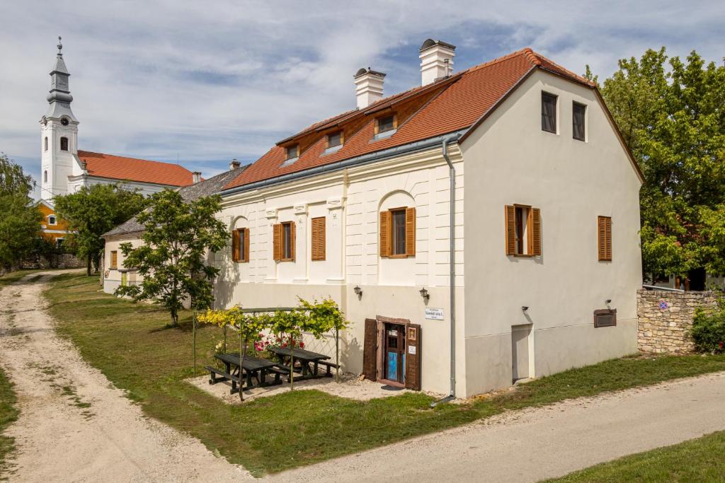 an old white house with a church in the background at Köveskál Vendégház in Köveskál