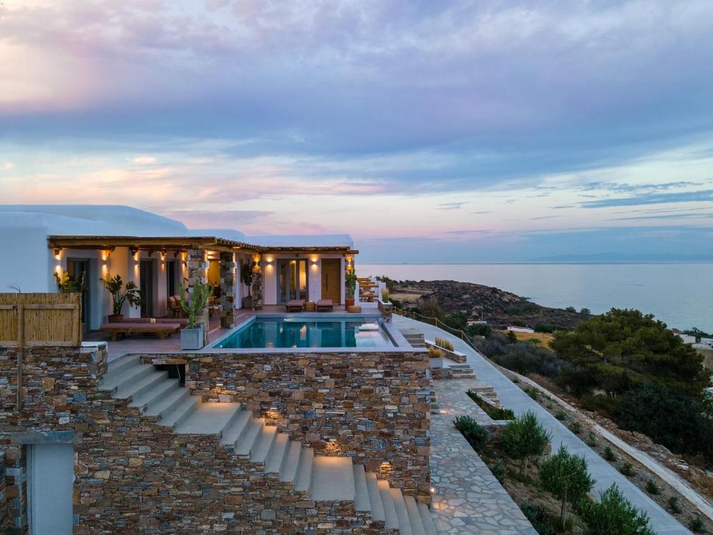 a house with a swimming pool and a stone wall at Villa Lefko in Ano Syros