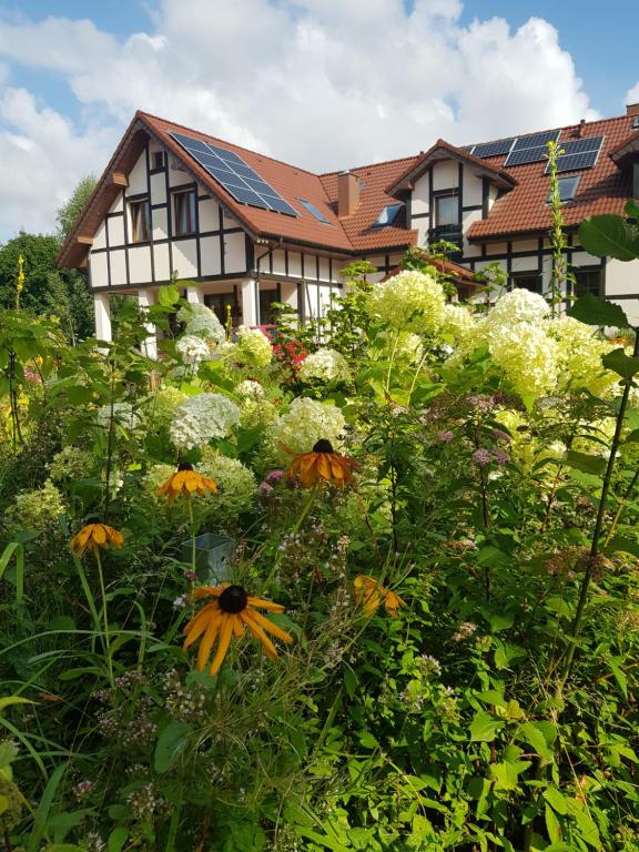 a house with a garden with flowers in front of it at Agroturystyka Gandelinka Park Kędrzyno in Kędrzyno