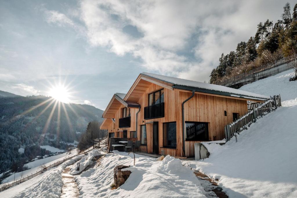 a cabin in the snow with the sun in the background at Chalet Tschogerhof Tiers am Rosengarten Dolomiten in Tires