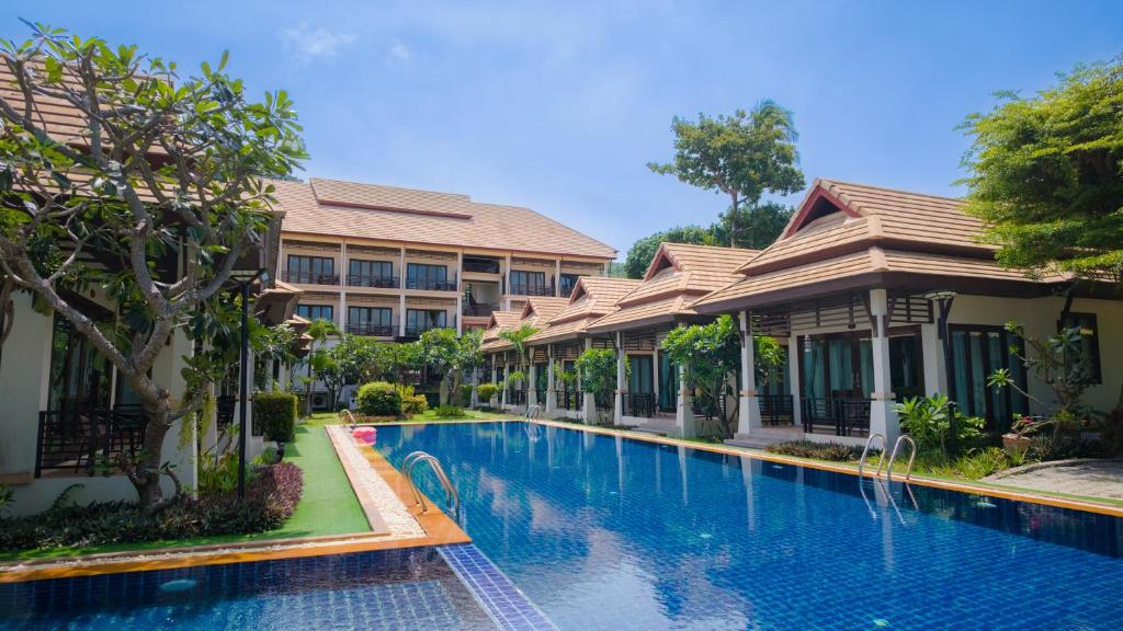 a swimming pool in front of some buildings at Poolsawat Villa - SHA Plus in Lamai