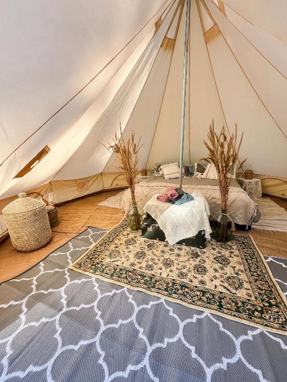 a tent with a bed and a rug in a room at Lahemaa Nature Glamping - Eha in Vihasoo