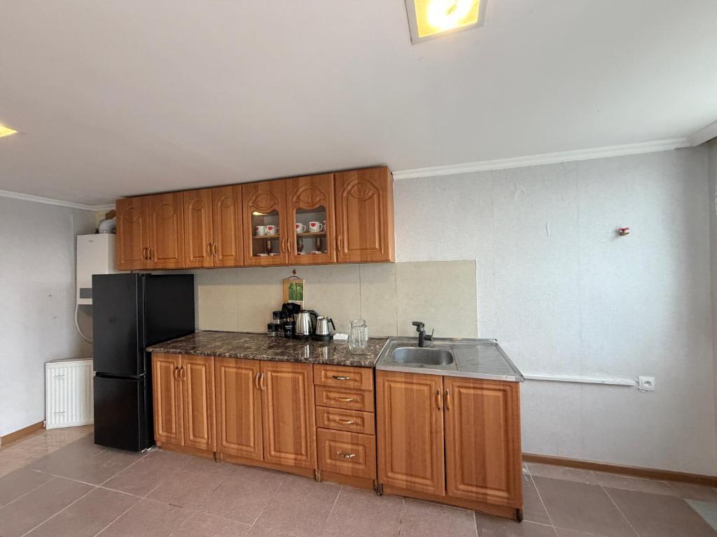 a kitchen with wooden cabinets and a black refrigerator at Grand hotel dmanisi in Dmanisi