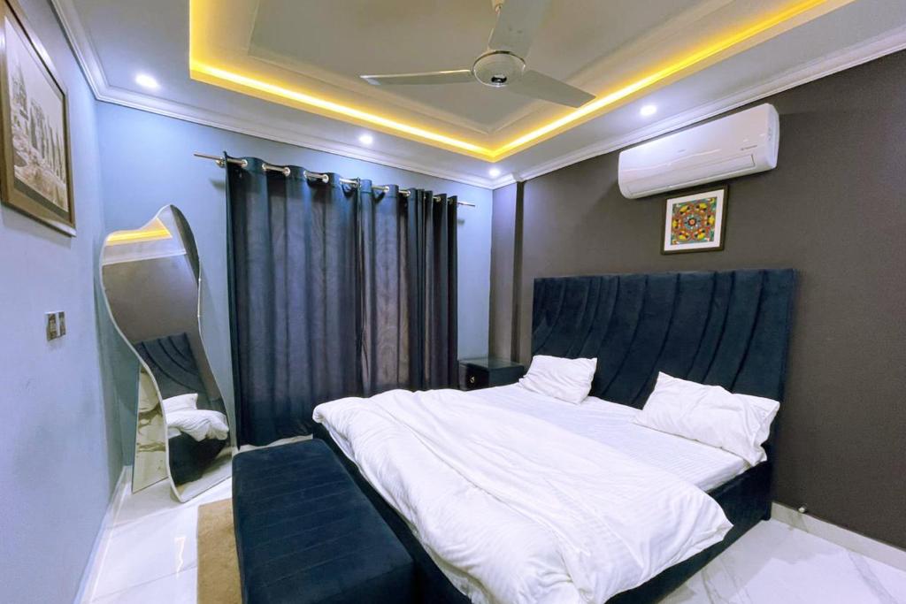 a bedroom with a large bed with a blue headboard at Bahria 777 Luxury Apartment in Lahore