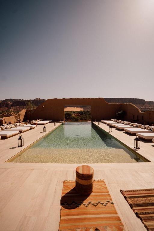 a large swimming pool with a bunch of lounge chairs at Dar Tantora The House Hotel in Al-ʿUla