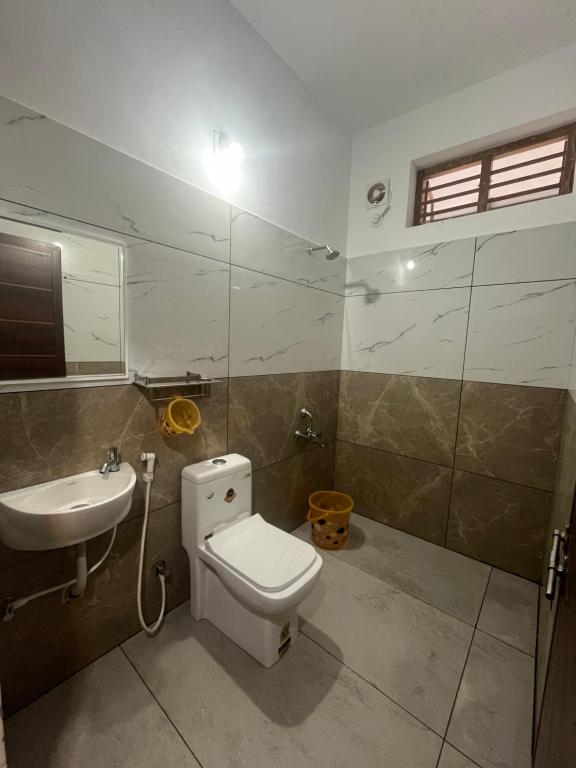 a bathroom with a toilet and a sink at Romins Park in Kodanad